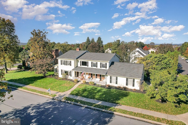 colonial-style house with covered porch and a front yard