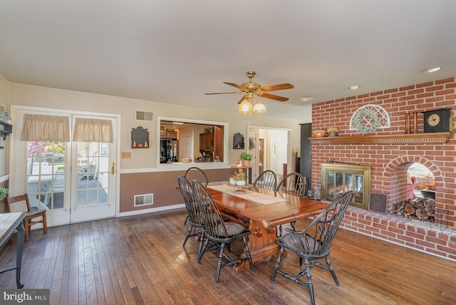 dining area with wood-type flooring, visible vents, a fireplace, and baseboards