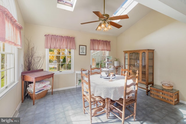 dining space featuring vaulted ceiling with skylight, a ceiling fan, and baseboards