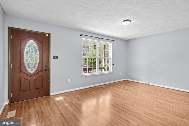 foyer entrance featuring visible vents, wood finished floors, baseboards, and a textured ceiling