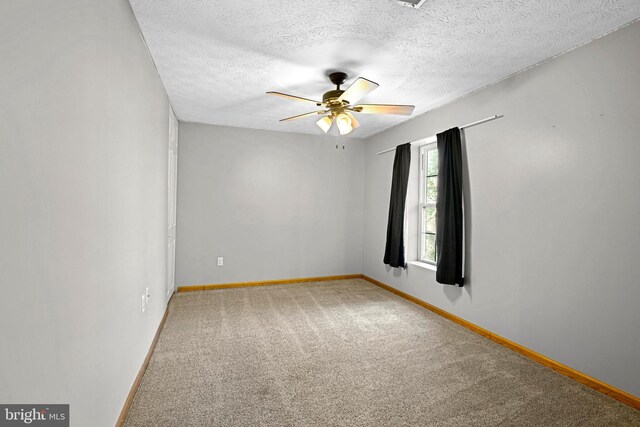 unfurnished room featuring baseboards, carpet floors, a textured ceiling, and ceiling fan