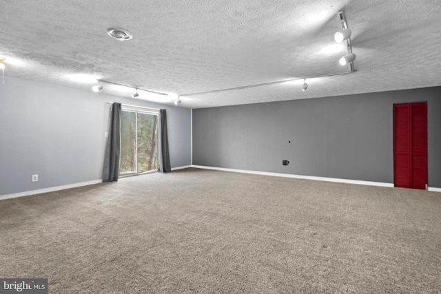 spare room with rail lighting, carpet, baseboards, and a textured ceiling