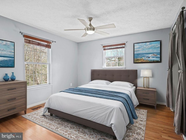 bedroom featuring a textured ceiling, wood finished floors, visible vents, and baseboards