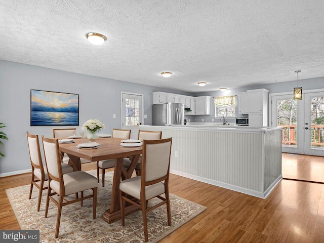 dining room with a wealth of natural light, baseboards, light wood-style floors, and a textured ceiling