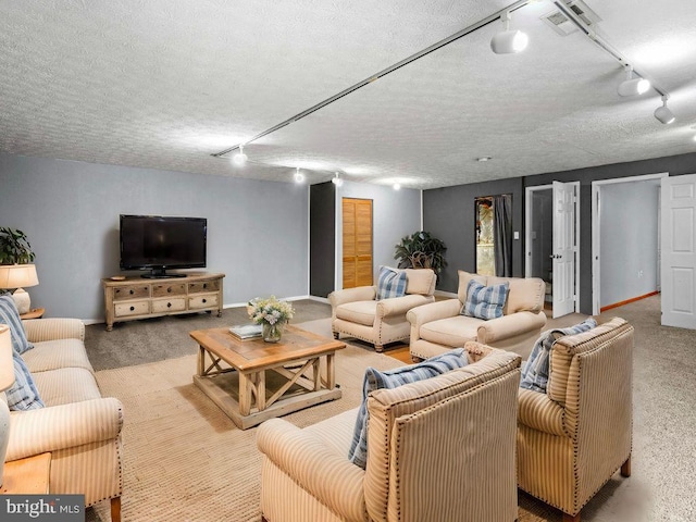 carpeted living area with visible vents, rail lighting, a textured ceiling, and baseboards