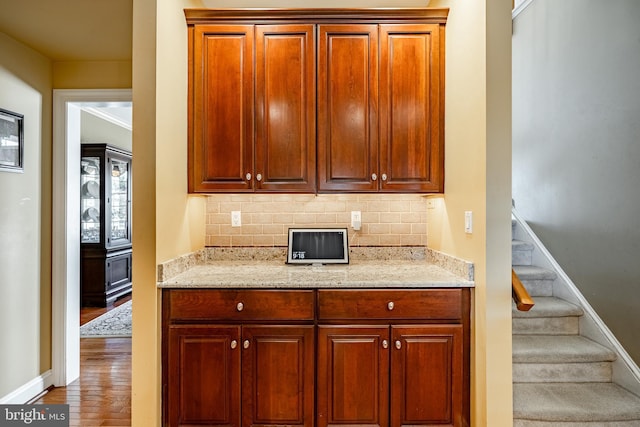 kitchen featuring tasteful backsplash, wood finished floors, and light stone countertops