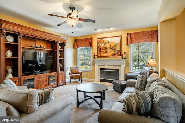 living area featuring a ceiling fan, baseboards, and a premium fireplace