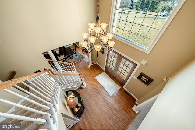 entryway featuring baseboards, stairway, french doors, wood finished floors, and a notable chandelier