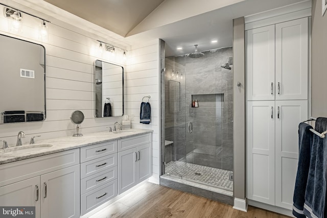 full bathroom with visible vents, a stall shower, wood finished floors, and a sink