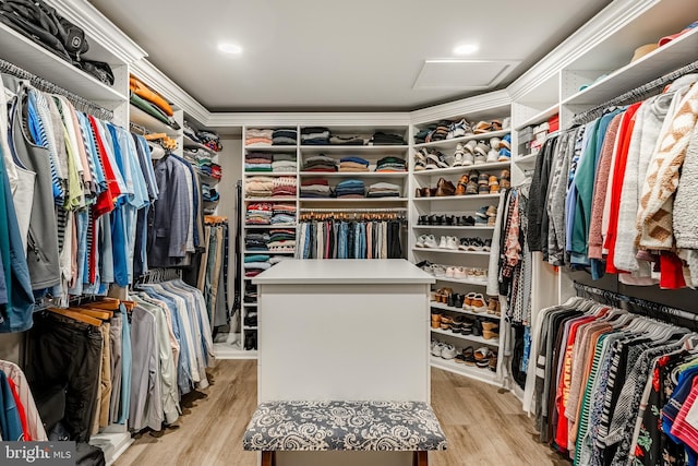 walk in closet with attic access and light wood-style flooring