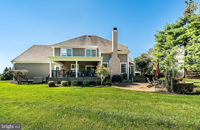 rear view of house with a yard, a chimney, and a patio area