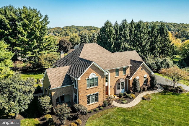 view of front facade featuring brick siding, a chimney, and a front lawn