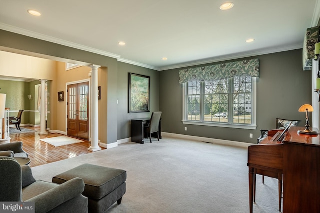 living area featuring baseboards, crown molding, ornate columns, and carpet floors