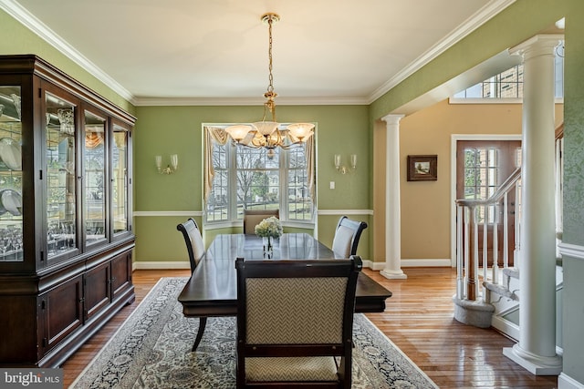 dining space featuring stairway, dark wood finished floors, decorative columns, ornamental molding, and a chandelier