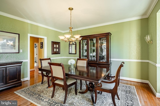 dining space featuring a notable chandelier, crown molding, baseboards, and wood-type flooring