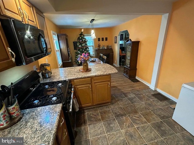 kitchen featuring visible vents, baseboards, a peninsula, hanging light fixtures, and black appliances