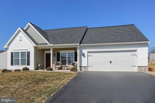 view of front facade with stone siding, a garage, driveway, and board and batten siding