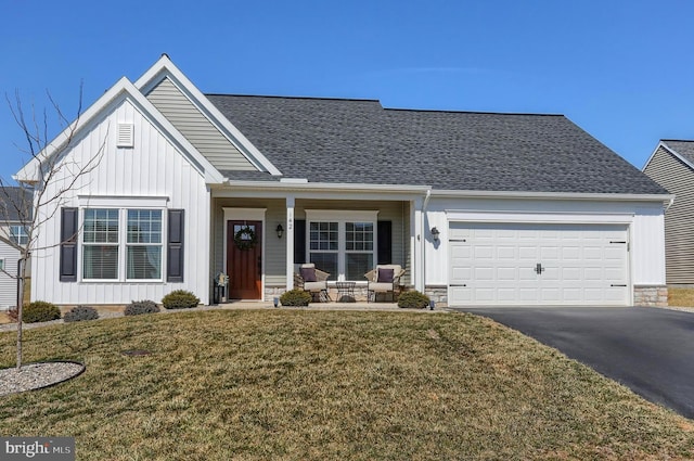 view of front of home featuring an attached garage, a shingled roof, a front lawn, aphalt driveway, and board and batten siding