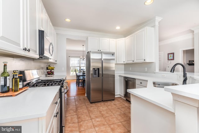 kitchen with crown molding, appliances with stainless steel finishes, a peninsula, white cabinets, and a sink