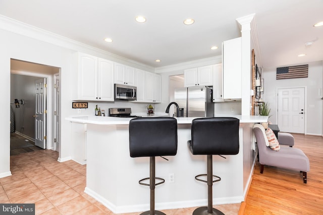 kitchen featuring stainless steel appliances, a peninsula, a breakfast bar area, and crown molding