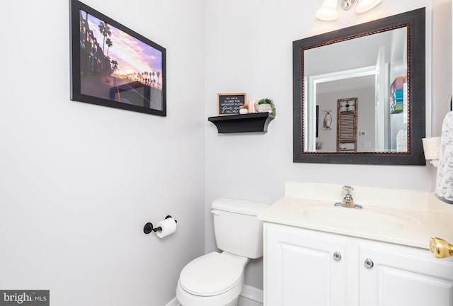 half bath with baseboards, toilet, and vanity