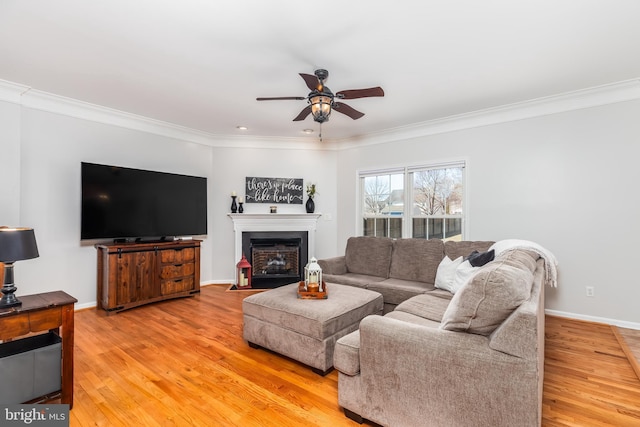 living area with a ceiling fan, light wood-type flooring, baseboards, and ornamental molding