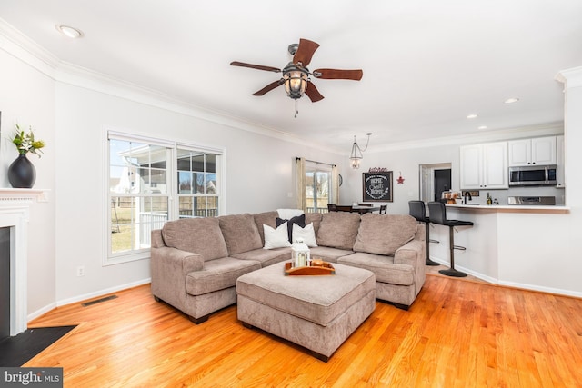 living room with visible vents, light wood-style flooring, and crown molding