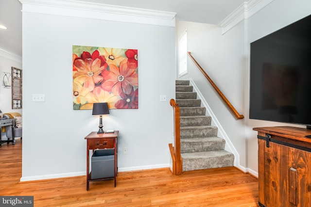 stairs with recessed lighting, wood finished floors, baseboards, and ornamental molding