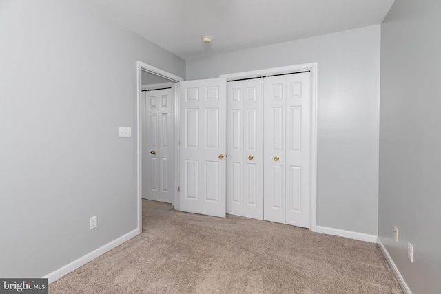 unfurnished bedroom featuring a closet, baseboards, and carpet floors