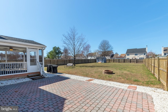 view of patio / terrace featuring an outdoor structure, a sunroom, a fire pit, and a fenced backyard