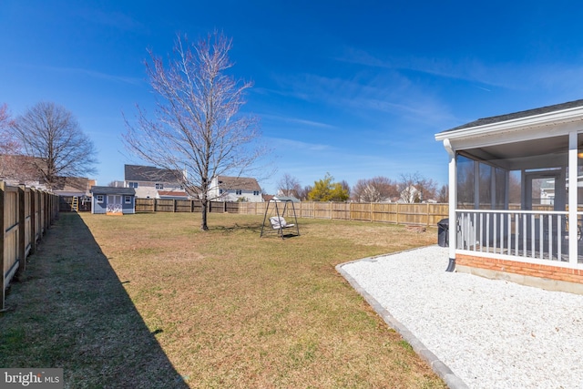 view of yard with an outdoor structure, a fenced backyard, and a sunroom