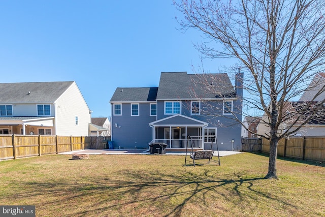 back of house featuring a patio area, a yard, a fenced backyard, and a sunroom