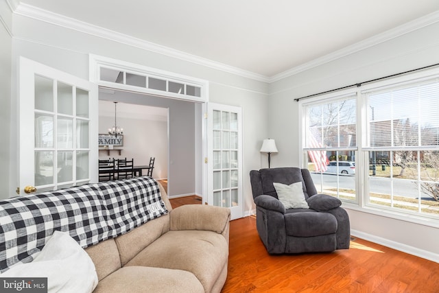 living room with baseboards, crown molding, an inviting chandelier, and wood finished floors