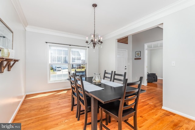 dining area featuring light wood-type flooring, baseboards, a notable chandelier, and crown molding