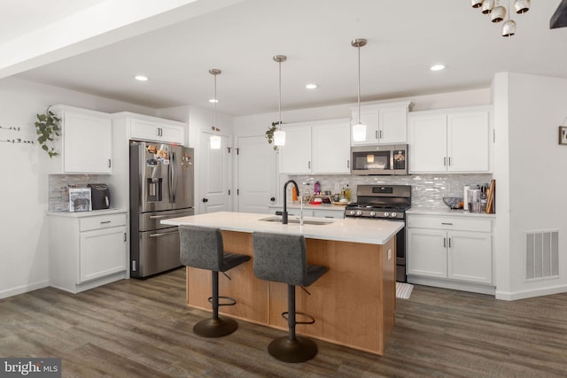 kitchen with visible vents, dark wood finished floors, white cabinets, stainless steel appliances, and a sink