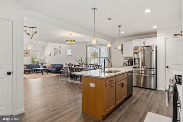 kitchen with decorative light fixtures, open floor plan, dark wood-style floors, stainless steel appliances, and a sink