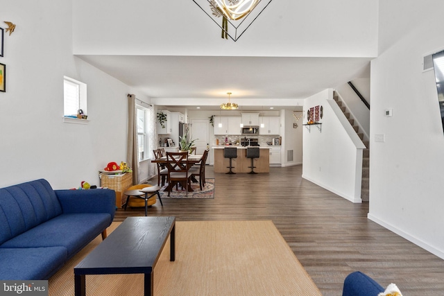 living area with visible vents, stairway, baseboards, and dark wood-style flooring