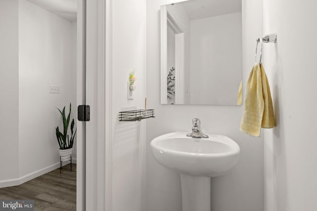 bathroom featuring wood finished floors, baseboards, and a sink