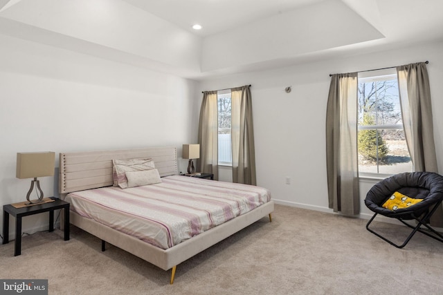 carpeted bedroom featuring recessed lighting, multiple windows, baseboards, and a tray ceiling