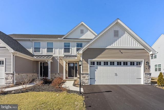 view of front of property featuring a garage, stone siding, board and batten siding, and driveway