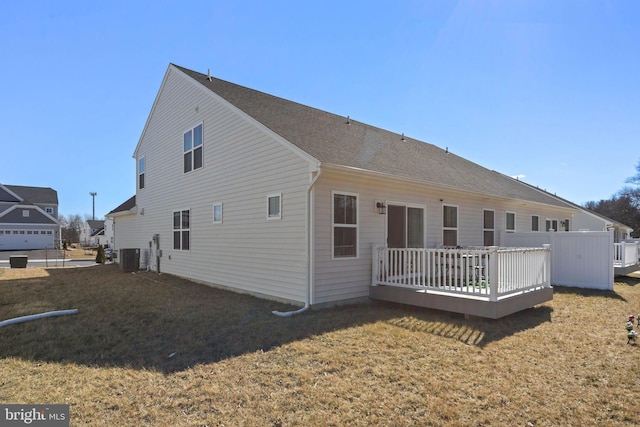 back of house with central air condition unit, a lawn, a shingled roof, and a deck