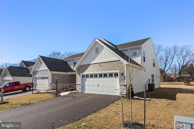 view of front facade featuring an attached garage, stone siding, aphalt driveway, central air condition unit, and board and batten siding