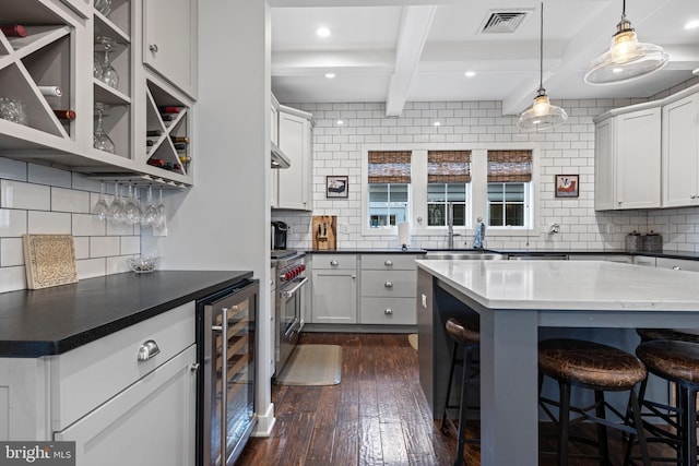 631 Monument Ave, Malvern, PA 19355 - kitchen with visible vents, beamed ceiling, beverage cooler, stainless steel stove, and dark wood-style flooring