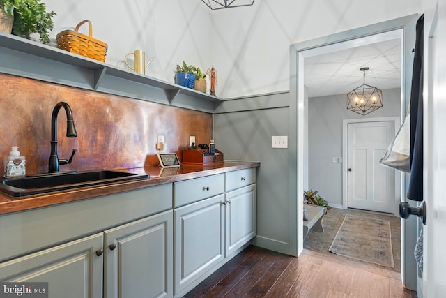 631 Monument Ave, Malvern, PA 19355 - bar featuring a sink, a chandelier, baseboards, and dark wood-style floors