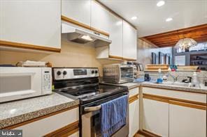 kitchen featuring white microwave, under cabinet range hood, stainless steel electric range oven, light countertops, and white cabinets