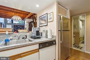 kitchen featuring a sink, wood finished floors, freestanding refrigerator, white cabinets, and dishwasher