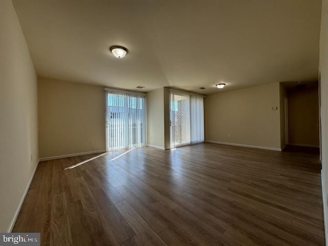 spare room with baseboards and wood finished floors