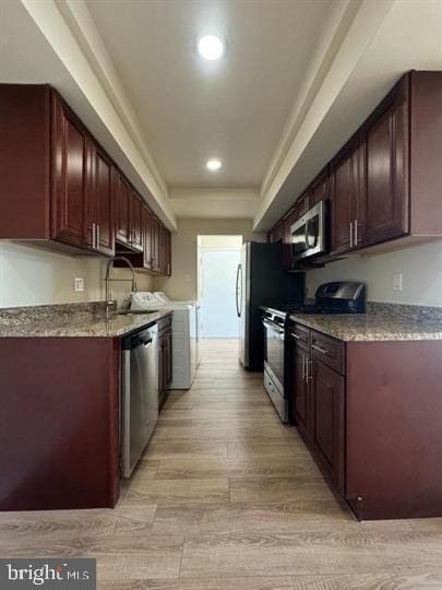 kitchen with light stone countertops, recessed lighting, light wood-style flooring, appliances with stainless steel finishes, and a sink