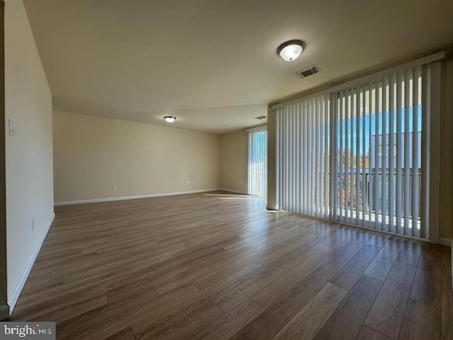 unfurnished room with visible vents, baseboards, and wood finished floors