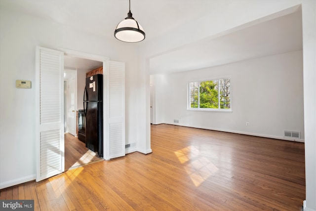 spare room featuring hardwood / wood-style floors, baseboards, and visible vents